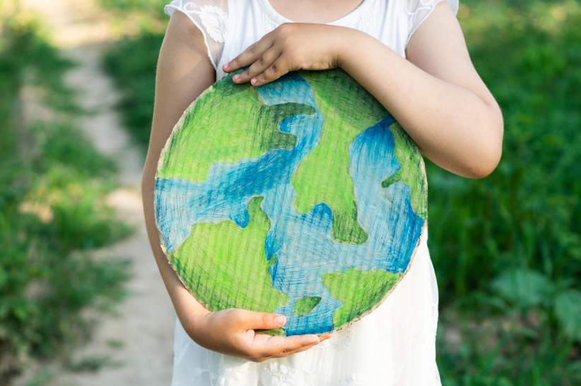A child holding a cardboard cutout of the Earth